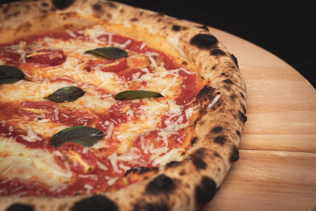 pexels-photo-12096782 Close-up of a freshly baked Margherita pizza with cheese, basil, and tomato sauce on a wooden board.